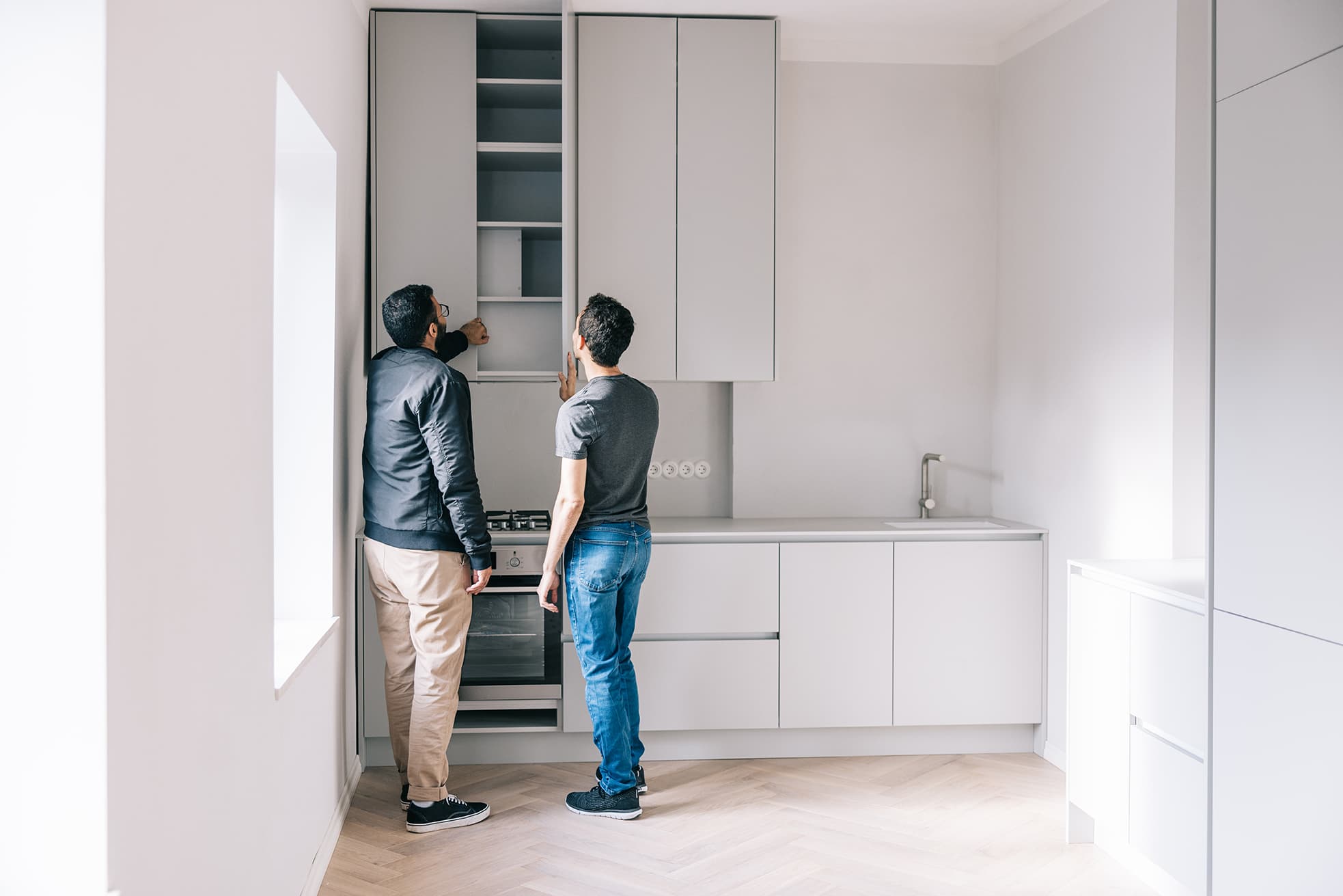 two people in white kitchen inspecting cabinets